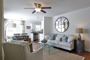 A living room with a white couch and a glass coffee table.